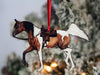 a brown and white horse ornament hanging from a christmas tree